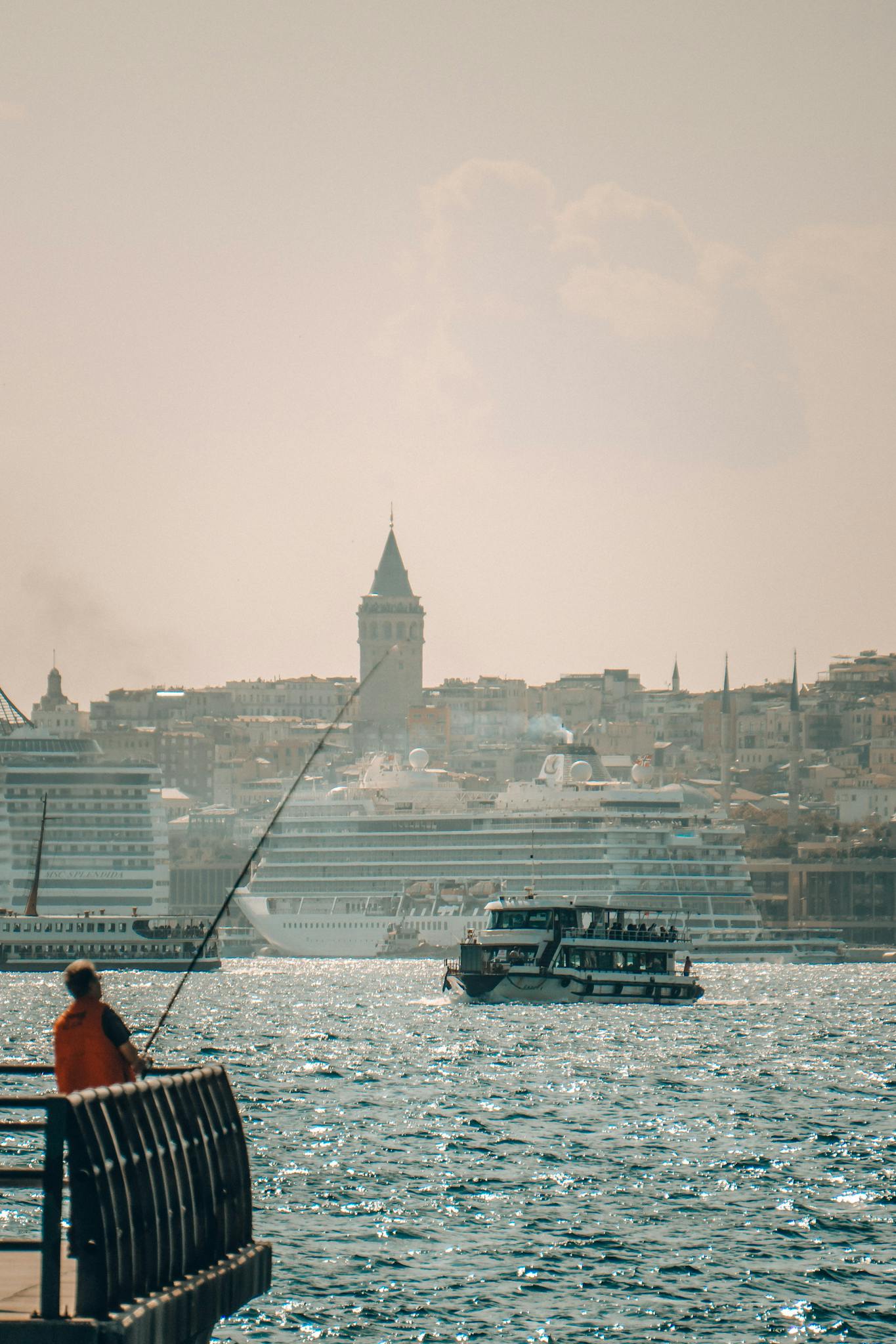 Explore the stunning scene of İstanbul with Galata Tower and boats in the Bosporus under a golden sunset.